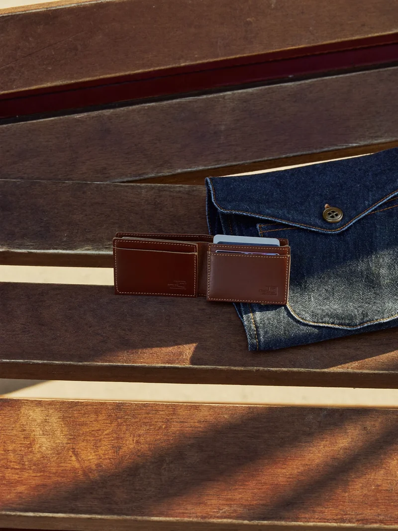 Portacarte e portachiavi in pelle su una panca in legno accanto a denim